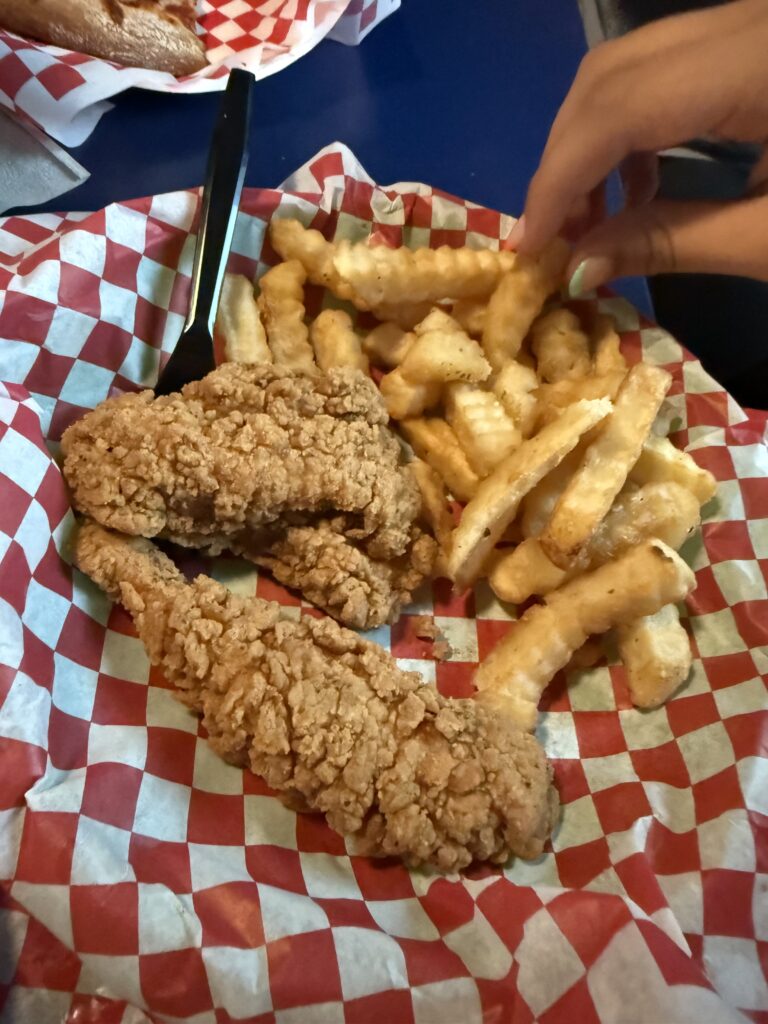 Chicken tenders and crinkle-cut fries on checkered paper at Sandbar Sports Grill