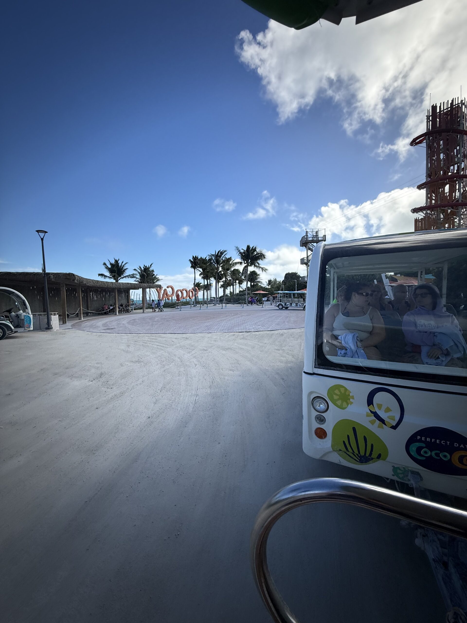 Passengers riding an island shuttle past the CocoCay sign and waterpark tower