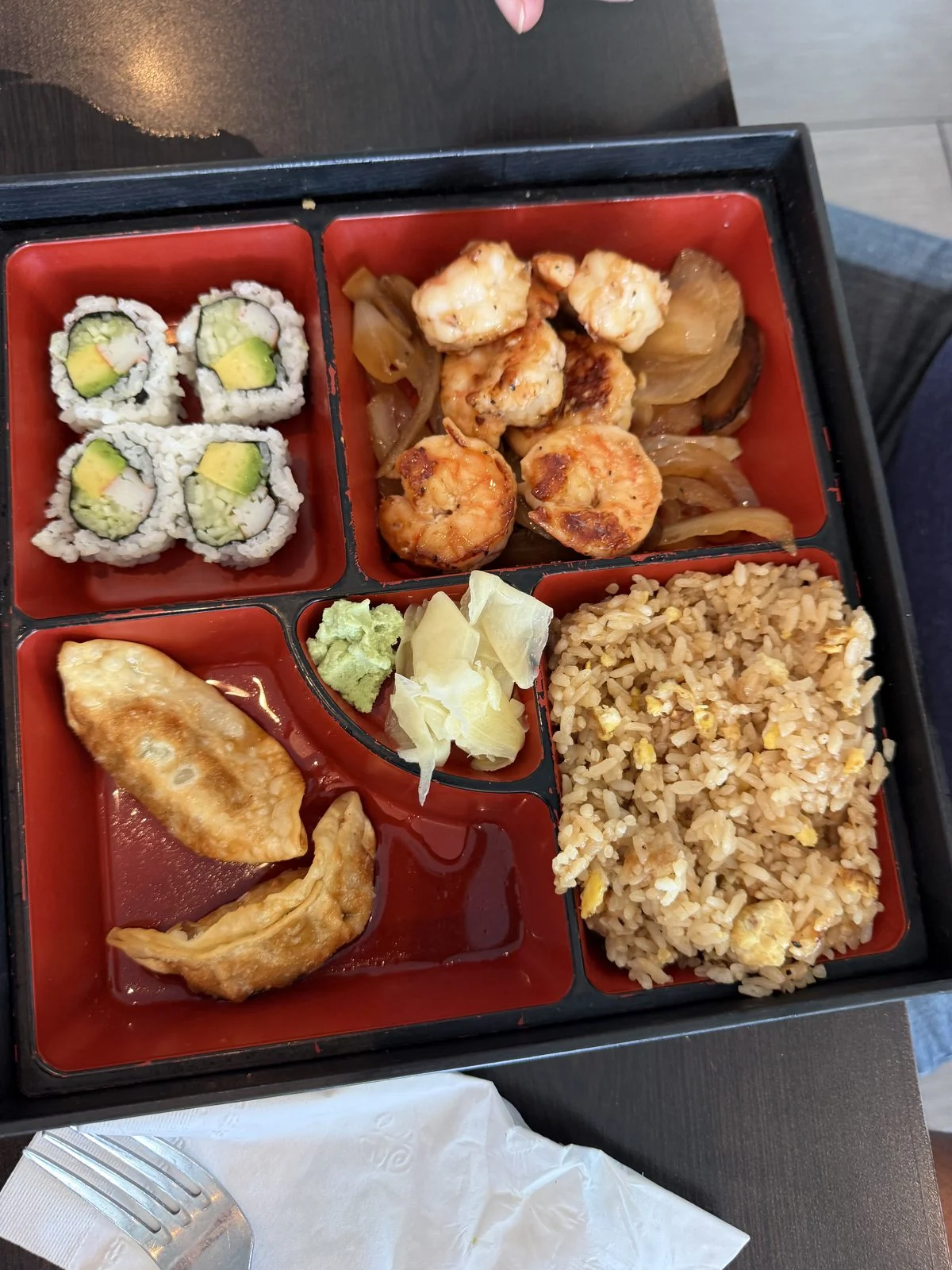 Bento box with hibachi, sushi rolls, fried rice, dumplings, pickled ginger, and wasabi at Kumo Sushi & Hibachi.