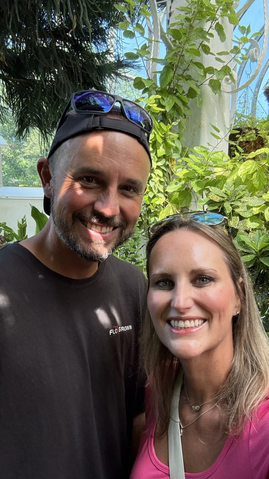 Jason and Danielle taking a selfie among sunlit tropical plants inside the Key West Butterfly & Nature Conservatory.