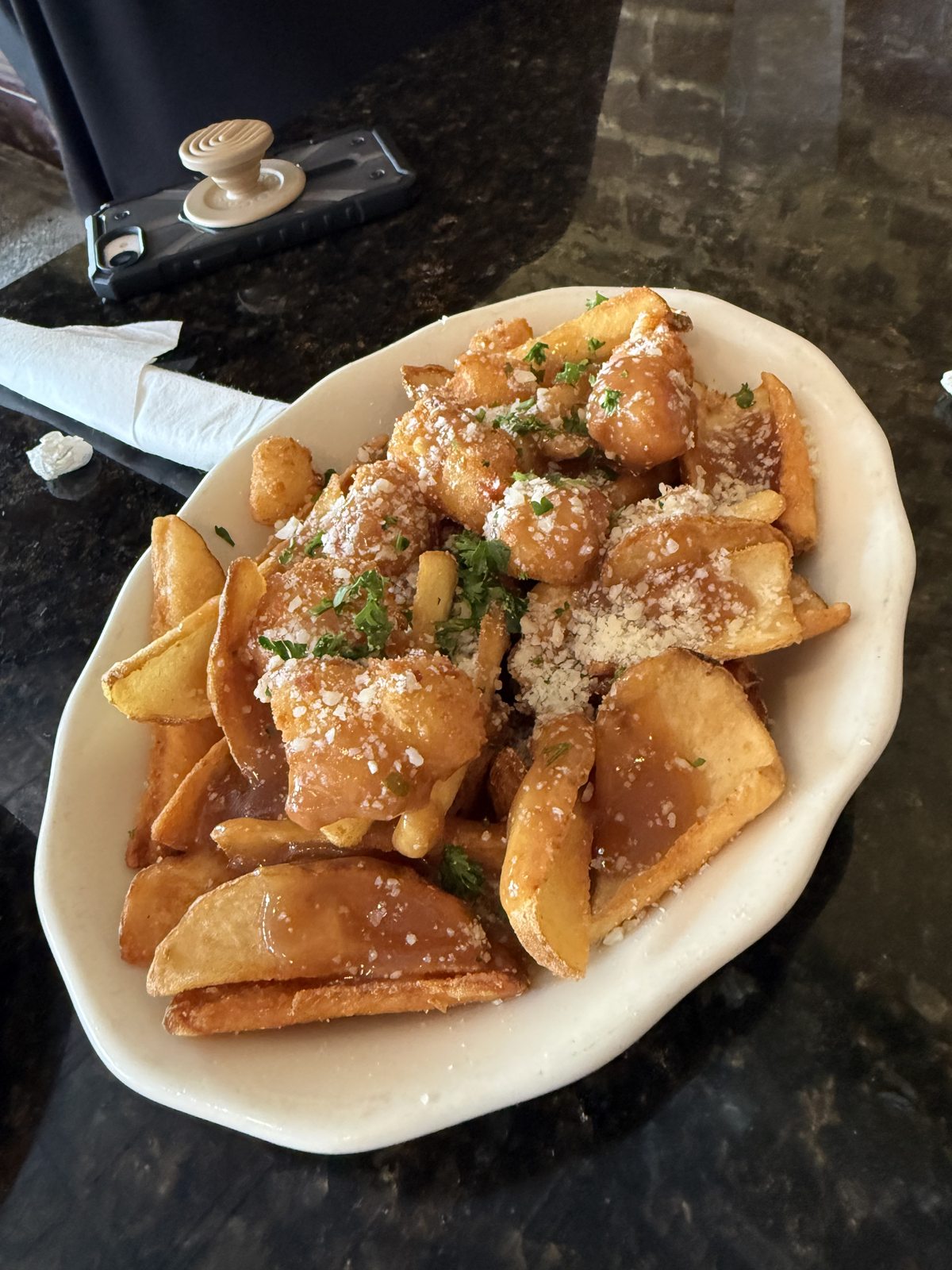 Potato wedges topped with gravy, grated cheese, and green herbs at McCracken’s Pub in Leesburg.