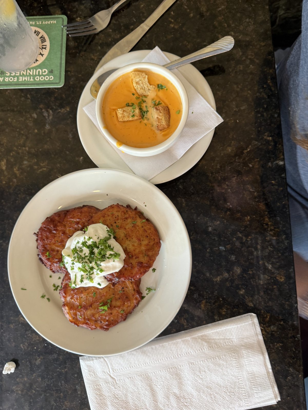 Orange soup beside a golden-brown round entrée topped with white cream and green herbs at McCracken’s Pub.