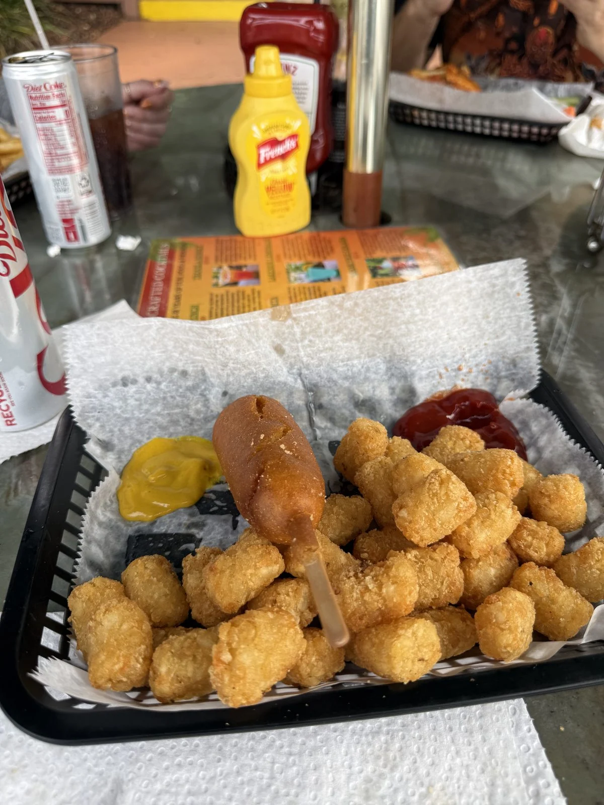 Corn dog and tater tots in a paper-lined basket with mustard and ketchup at Tiki Bar & Grill in Minneola.