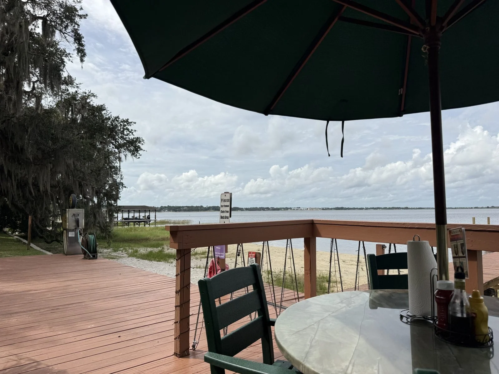 Umbrella-shaded table on the wooden deck overlooking Lake Minneola at Tiki Bar & Grill.
